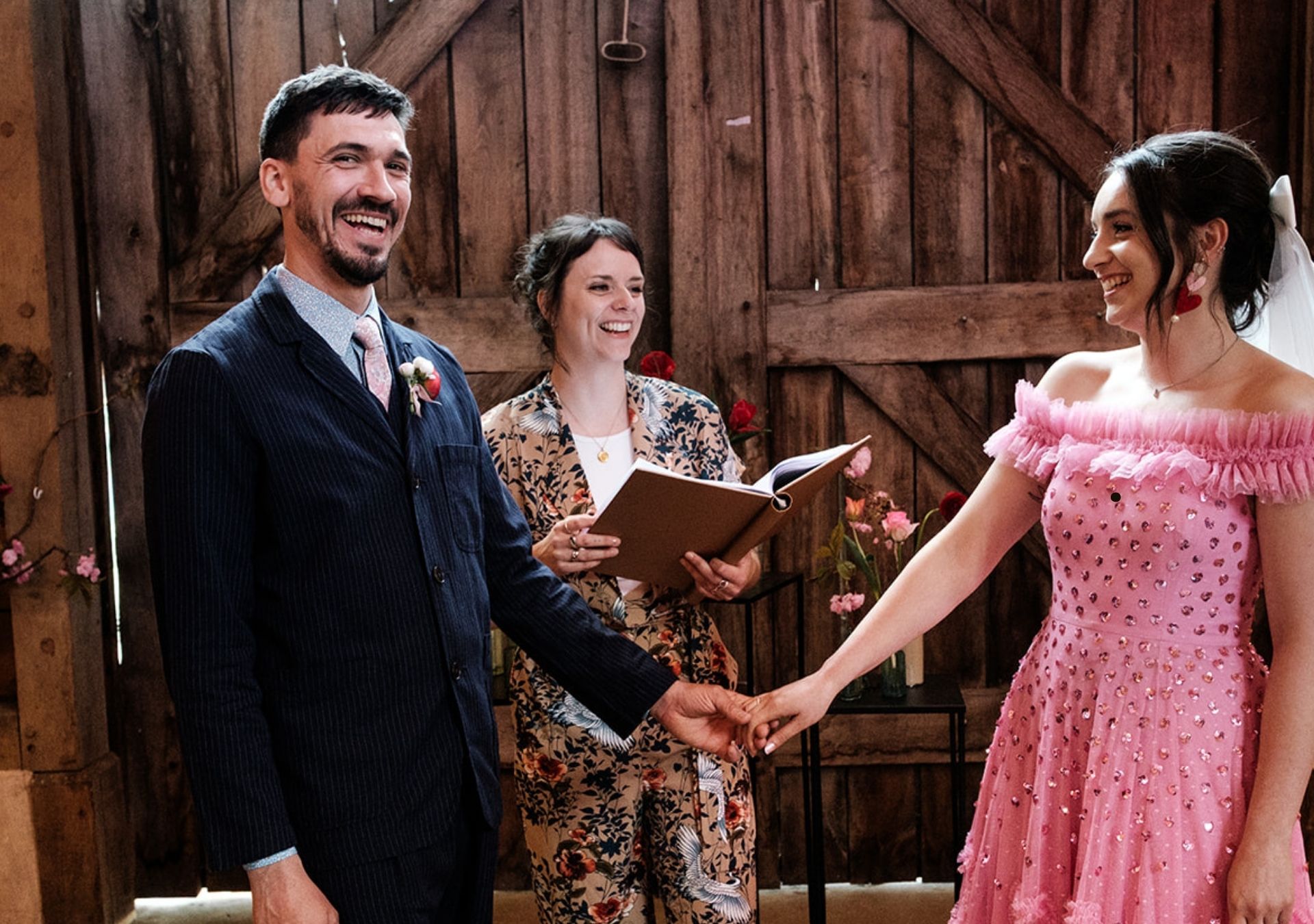 Hannah, an Alternative Wedding Celebrant, is officiating the wedding of a very happy couple. The are all smiling and laughing.