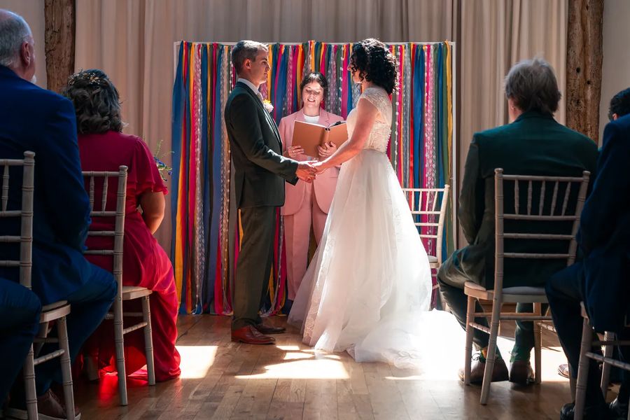 Hannah, an alternative wedding celebrant, is standing at the altar while the couple hold hands.