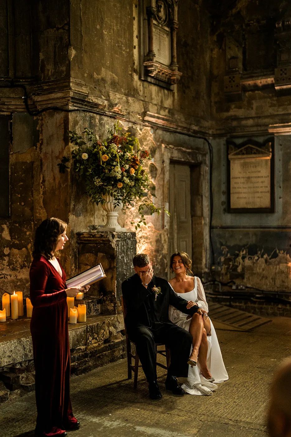 Hannah is reading aloud from her ceremony script as a couple looks on laughing and smiling.